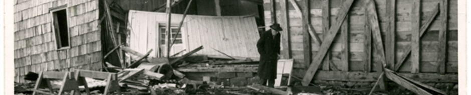 Dionisio Muñoz camina entre los escombros de un salón de billar. Año 1960. Ancud. Donada por José Caro Bahamonde.