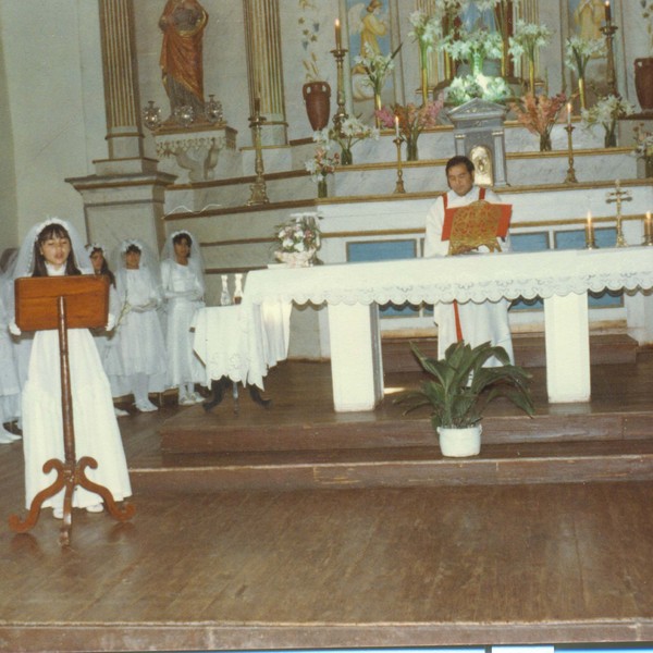 Niña exponiendo junto a niñas y sacerdote en Parroquia de Carén